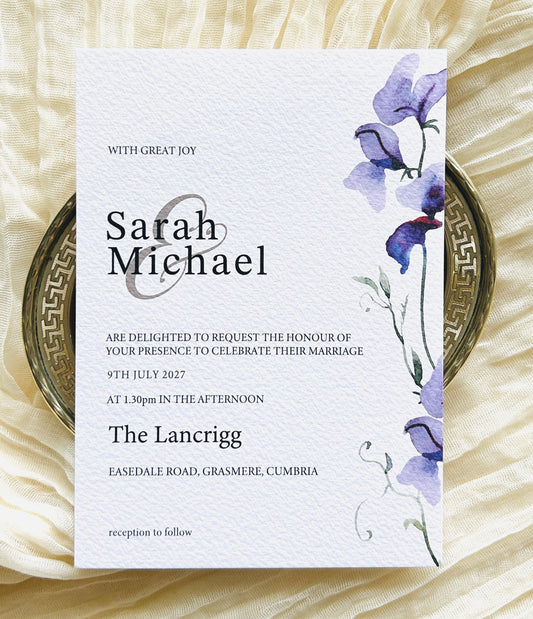 Wedding invitation card with a purple floral design 
